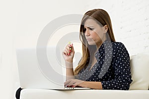 Woman using laptop computer networking or online internet shopping at home couch