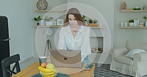 Woman using laptop computer. Portrait of business woman watching news at laptop screen and drinking coffee at home