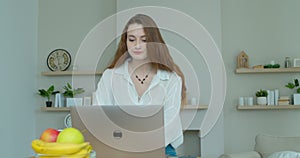 Woman using laptop computer. Portrait of business woman watching news at laptop screen and drinking coffee at home