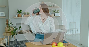 Woman using laptop computer. Portrait of business woman watching news at laptop screen and drinking coffee at home