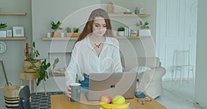 Woman using laptop computer. Portrait of business woman watching news at laptop screen and drinking coffee at home