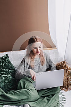 Young woman working on computer in bed. Relaxing at home. photo