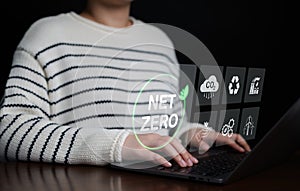 Woman using laptop computer working with Net Zero icons. Climate neutral long term strategy. Decarbonization sustainability, photo
