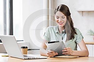 Woman using laptop and digital tablet in office. Entrepreneur, businesswoman, freelance worker, student working on computer. photo