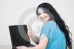 Woman using laptop and giving thumbs up