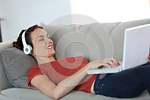 Woman using laptop and headphones on couch
