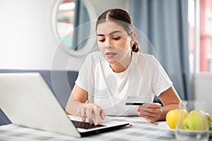 Woman using laptop and holding credit card