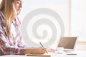 Woman using laptop and notepad