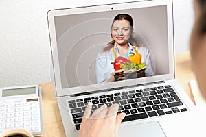 Woman using laptop for online consultation with nutritionist via video chat photo
