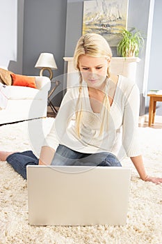 Woman Using Laptop Relaxing Sitting On Rug At Home