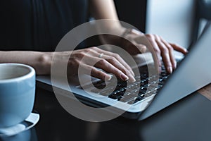 Woman using laptop, searching web, browsing information, having workplace at home or in creative office or cafe.