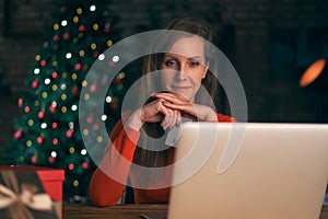 Woman using laptop, shopping online, using credit card at home. Christmas tree in the background