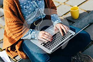 Woman using laptop while sitting on cement stairs