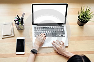 Woman using laptop on table in office room on windows with trees and nature background.