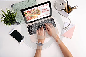 Woman using laptop to order food delivery at table