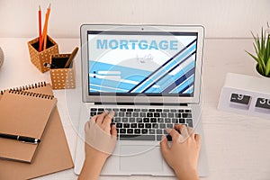 Woman using laptop to pay mortgage loan online at home