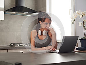 woman using laptop to watch online fitness webinar at home