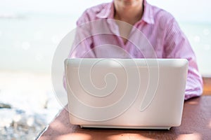 Woman using laptop to work study on work desk with clean nature beach outdoor background. Business, financial concept