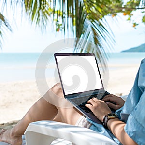 Woman using laptop with white screen background to work study on vacation days at beach background. Business, financial, trade
