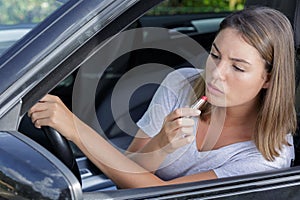 woman using lipstick while driving car