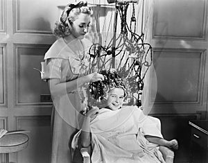 Woman using machine to style teenage girls hair