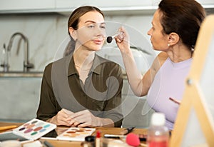 Woman using makeup brush to apply blush to bestie face