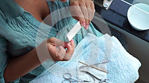 Woman using manicure scissors for cut cuticle and filing nail with nail file while home manicure. Close up. Home
