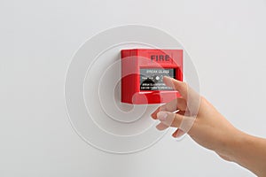 Woman using manual call point of fire alarm system