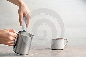 Woman using milk frother device in pitcher