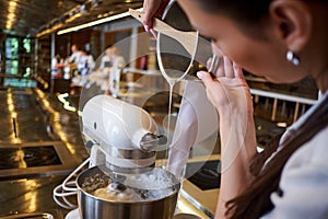 Woman using mixer standing at counter in her apron. Making dessert in pastry shop