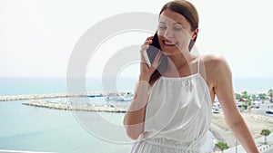 Woman using mobile on balcony. Female on vacation talking with friend via cellphone in slow motion