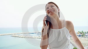 Woman using mobile on balcony. Female on vacation talking with friend via cellphone in slow motion