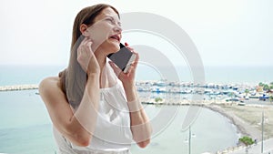 Woman using mobile on balcony. Female on vacation talking with friend via cellphone in slow motion