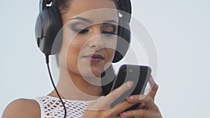 Woman using mobile cell smart phone on beach wearing earphones for music or talking Girl in bikini using smartphone