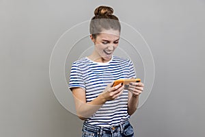 Woman using mobile phone with attentive focused expression, playing video game on cellphone.