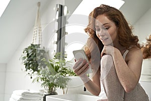 Woman using the mobile phone in bathroom