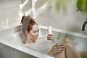 Woman using the mobile phone in bathroom