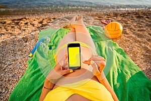 Woman using mobile phone on the beach