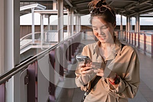 Woman is using mobile phone on the city bridge in Bangkok.