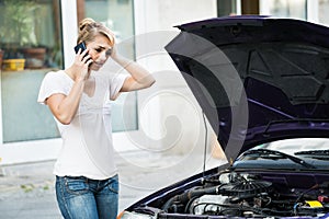 Woman Using Mobile Phone While Looking At Broken Down Car