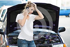 Woman Using Mobile Phone While Looking At Broken Down Car