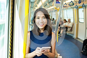 Woman using mobile phone in metro compartment