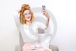 Woman using mobile phone for Online video chat on white. Joyful woman holding mobile phone smiling on camera while taking selfie,