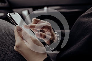 Woman using mobile phone over dark background in car. Close up beautiful hands holding smartphone. Female using