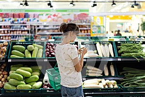 Woman using mobile phone while shopping in supermarket