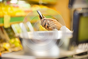 Woman using mobile phone while shopping in supermarket