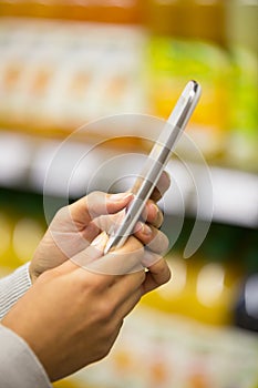 Woman using mobile phone while shopping in supermarket