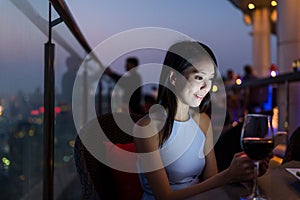 Woman using mobile phone at sky bar