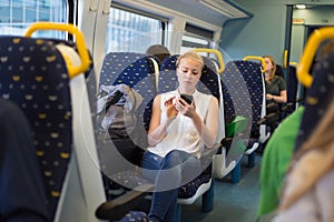 Woman using mobile phone while travelling by train.