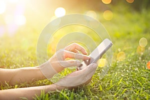 Woman using mobile smart phone outdoor in the sunrise on nature